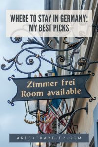 Pinterest graphic with the text "Where to Stay in Germany: My Best Picks". The picture is of a elaborate wrought-iron balcony on an old style building that has a sign that says "Zimmer frei Room available".