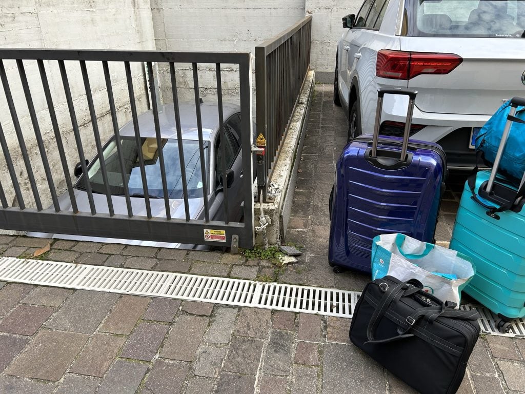 A parking area near Padua with travel luggage and a vehicle by a gated space, representing travel readiness. A reminder for those exploring what to see and do around Padua.