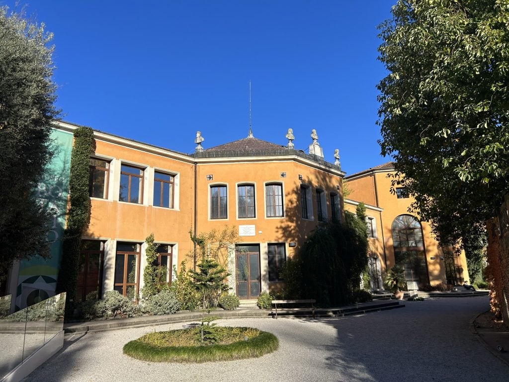 The Botanical Museum in Padua, a bright orange building surrounded by lush greenery, perfect for history and plant lovers. A highlight of Padua’s botanical garden experience.