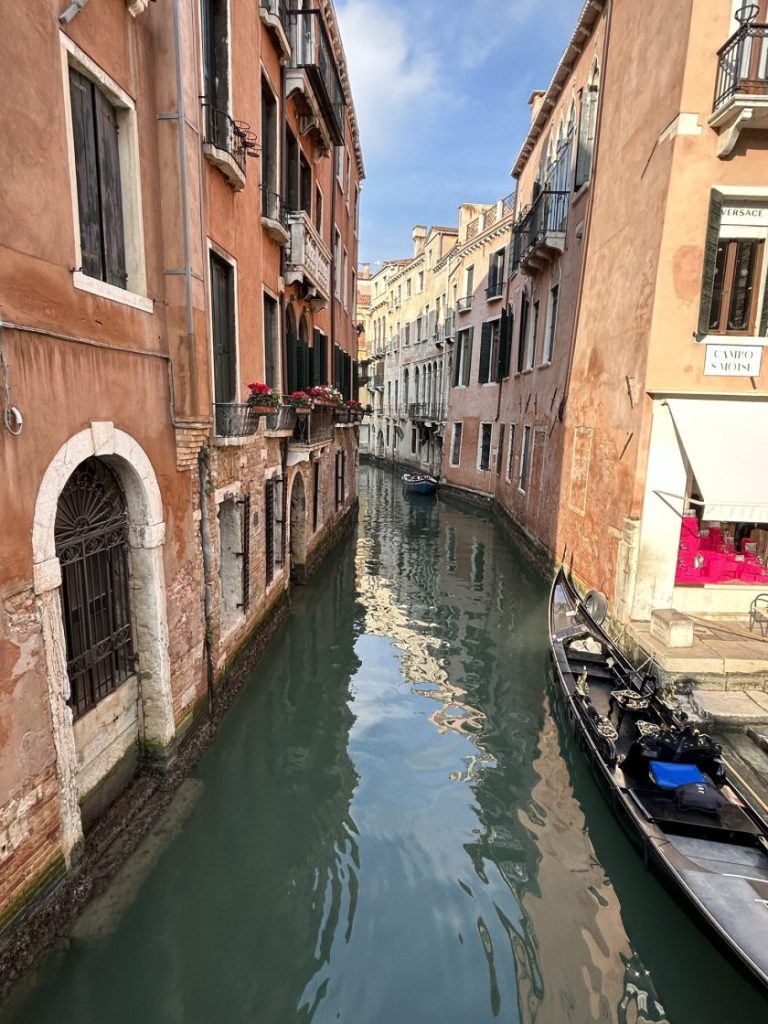 A serene canal in Venice with gondolas and colorful buildings, showcasing the city's tranquil side. An easy excursion from Padua for a romantic or relaxing outing.