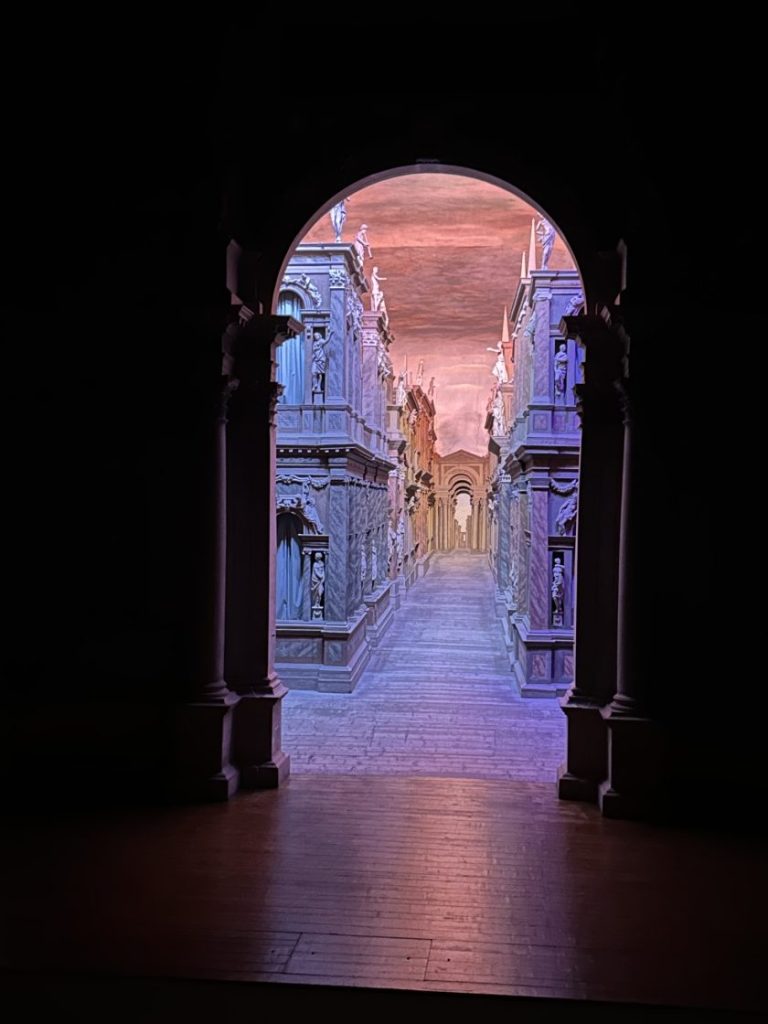 A dramatic perspective of the stage set at the Teatro Olimpico, with vivid lighting and intricate sculptures. An unforgettable cultural experience near Padua.