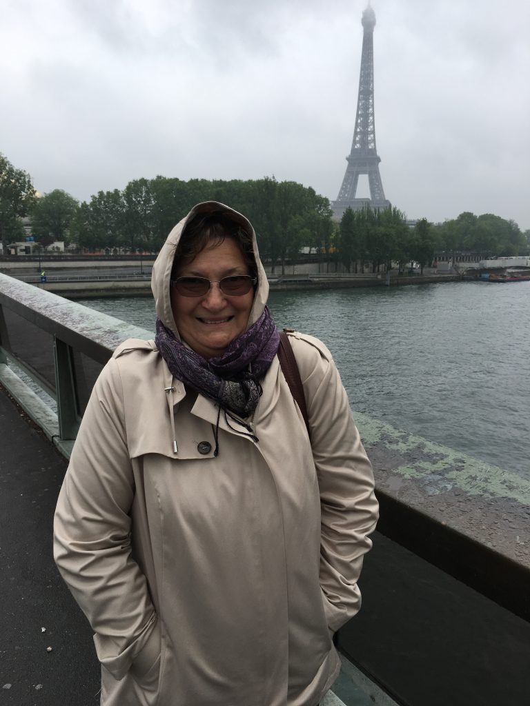 Carol Cram in front of the Eiffel Tower on a rainy day in May