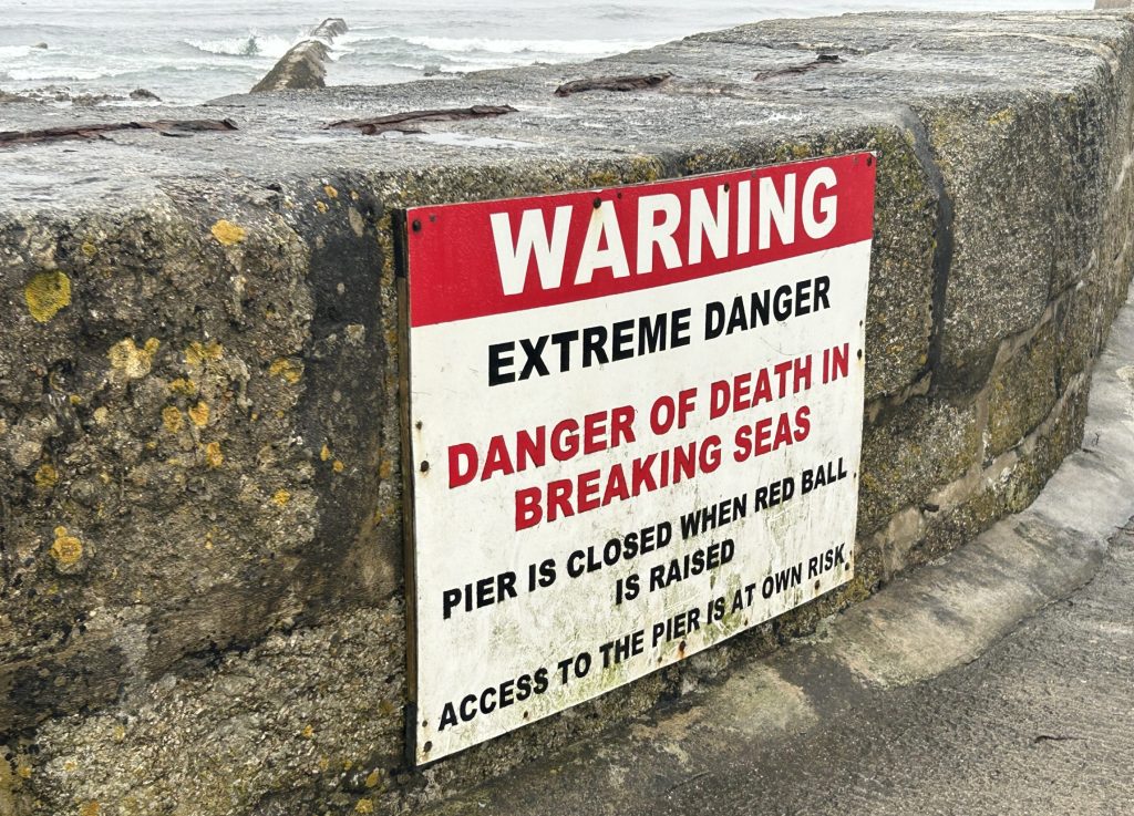 Warning sign on Porthleven pier on a Rabbie’s tour of southwest England