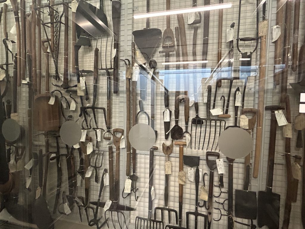 A large collection of farm implements in the open storage area of the museum