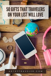 Pinterest graphic with the text 50 gifts that travelers on your list will love. The picture is a selection of travel accessories including a Smartphone, passport, coins, a watch, a toy plane and headphones.