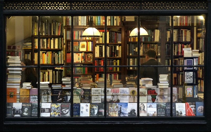 Storefront of a very crowded bookstore in England with books in the window and on shelves behind. The feeling is literary and slightly antique.