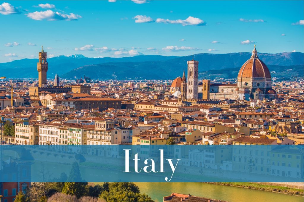 A panoramic view of Florence, Italy, featuring the iconic red dome of the Florence Cathedral, the Palazzo Vecchio’s clock tower, and the densely packed terracotta rooftops with distant hills on the horizon.