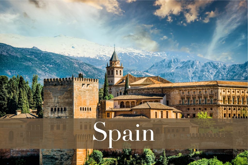 The Alhambra in Granada, Spain, with historic Moorish architecture and the Sierra Nevada mountains in the background.