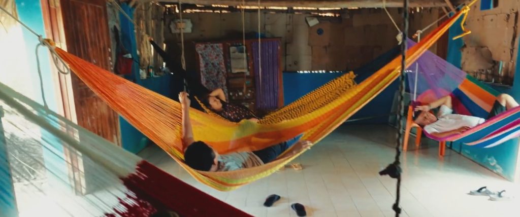 People swinging in colorful hammocks in the home of Maya people in the Yucatan peninsula in Mexico. A screenshot from the documentary film Beyond the Ruins.